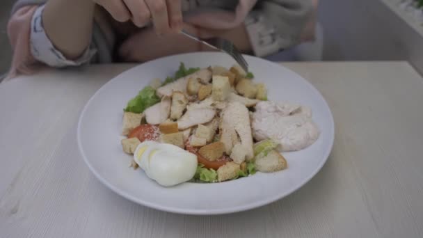 Young beautiful woman eats caesar salad in a cafe — Stock Video