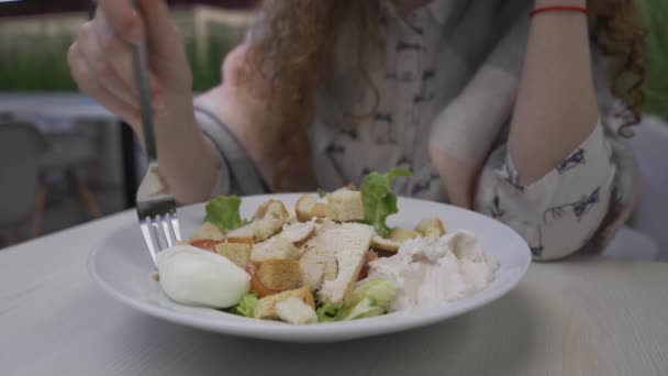 Genç güzel kadın bir kafede Sezar salatası yiyor — Stok video