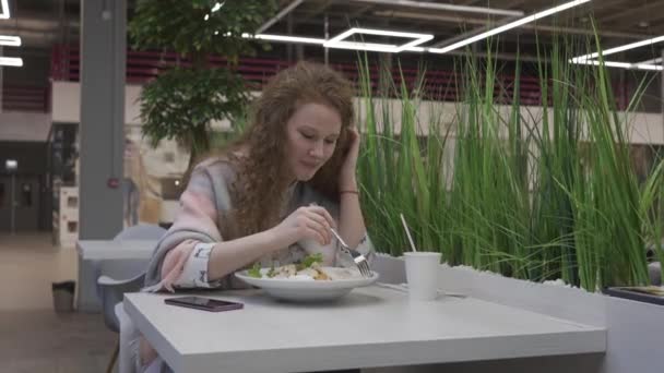 Joven hermosa mujer come ensalada César en un café — Vídeos de Stock