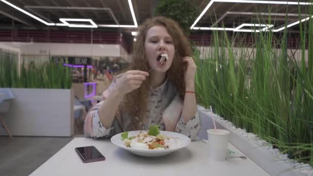 Joven hermosa mujer come ensalada César en un café — Vídeo de stock