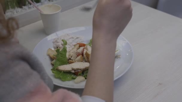 Young beautiful woman eats caesar salad in a cafe — Stock Video