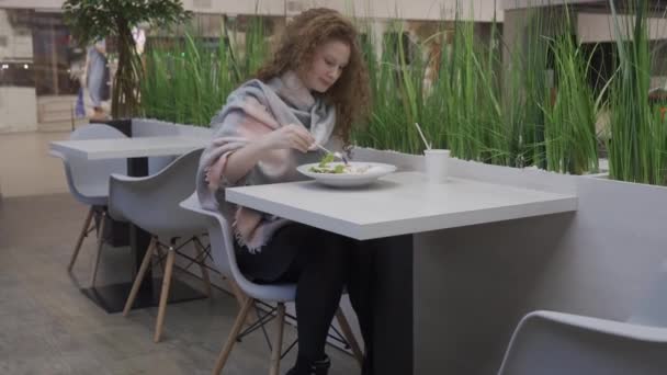 Joven hermosa mujer come ensalada César en un café — Vídeos de Stock