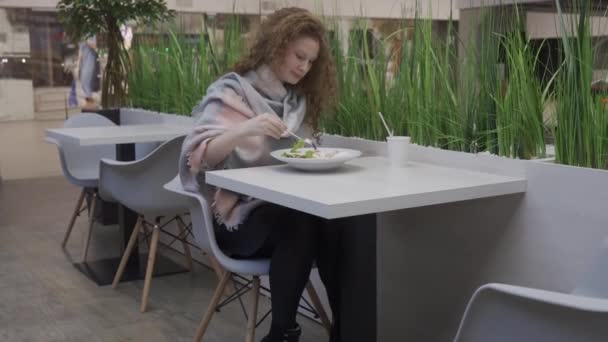 Joven hermosa mujer come ensalada César en un café — Vídeo de stock