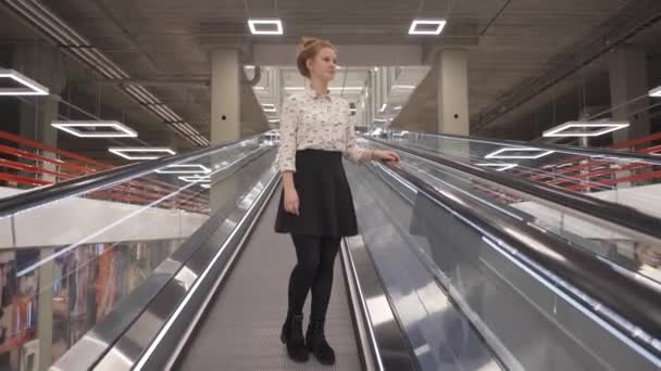 Genç güzel kız üzerinde doğrudan bir yürüyen merdiven iner — Stok video