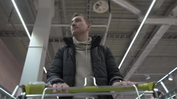 Joven hermoso hombre camina a través del supermercado. vista desde el carrito de compras — Vídeo de stock