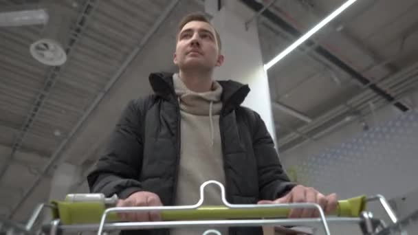 Joven hermoso hombre camina a través del supermercado. vista desde el carrito de compras — Vídeos de Stock