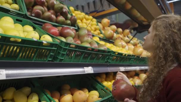 Mooie jongedame in de supermarkt kiest mango — Stockvideo