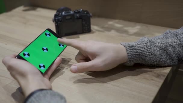 Primer plano de un hombre sosteniendo un teléfono inteligente de pantalla verde y viendo fotos desde una cámara — Vídeos de Stock