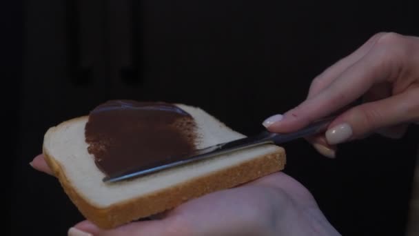 Closeup vídeo: espalhar manteiga de chocolate em um pedaço de pão — Vídeo de Stock