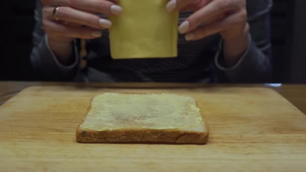 Donna mette una fetta di formaggio su pane e burro — Video Stock