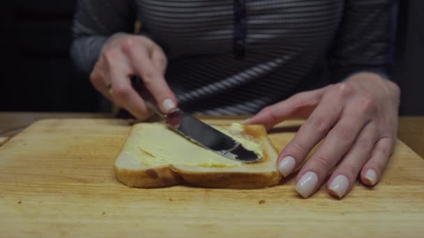 Frau streicht Butter auf Brot und legt eine Scheibe Käse — Stockvideo