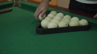 Bir adam bilardo topları koyar