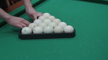 Bir adam bilardo topları koyar
