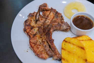 Patates ve salatalar ile beyaz bir tabak üzerinde biftek.