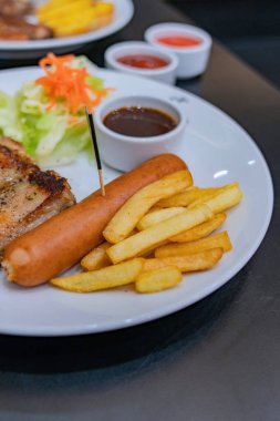 Patates ve salatalar ile beyaz bir tabak üzerinde biftek.