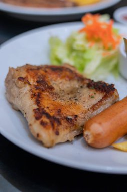 Patates ve salatalar ile beyaz bir tabak üzerinde biftek.