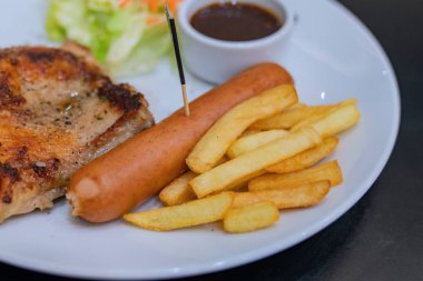 Patates ve salatalar ile beyaz bir tabak üzerinde biftek.