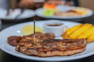 Patates ve salatalar ile beyaz bir tabak üzerinde biftek.