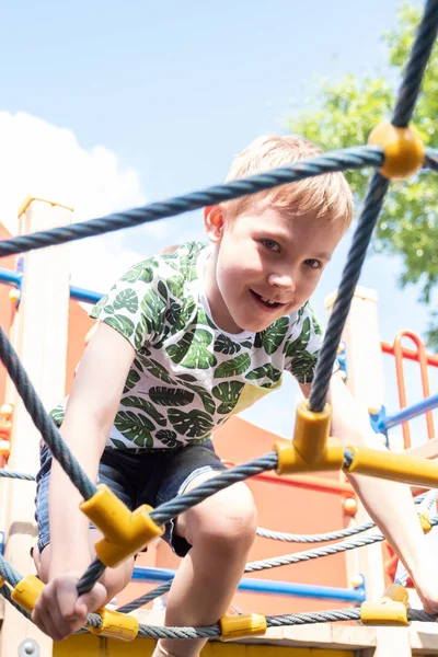 Netter Junge hat Spaß und klettert auf dem Spielplatz im Freien. — Stockfoto