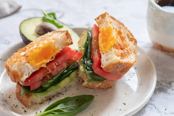 Egg in a hole sandwich with avocado, spinach and tomato