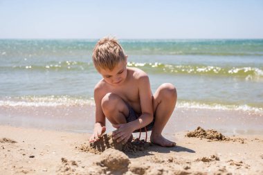 Kum ile plajda oynayan mutlu çocuk