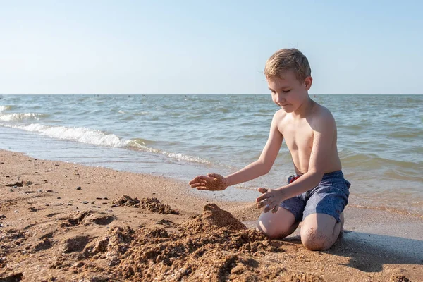 Šťastné dítě hraje s pískem na pláži — Stock fotografie