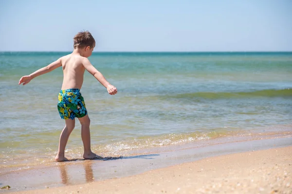 Criança feliz brincando com areia na praia — Fotografia de Stock