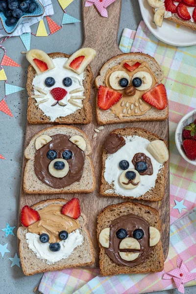 Hayvan yayılır, muz, çilek ve yaban mersini ile tost yüzleri — Stok fotoğraf