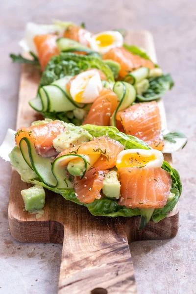 Листя салату, загорнуте копченим лососем, зі свіжим огірком, авокадо та яйцями — стокове фото
