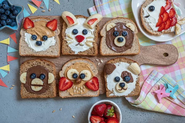 Funny animal faces toasts with spreads, banana, strawberry and blueberry — Stock Photo, Image