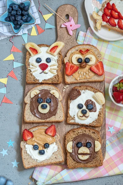 Funny animal faces toasts with spreads, banana, strawberry and blueberry — Stock Photo, Image