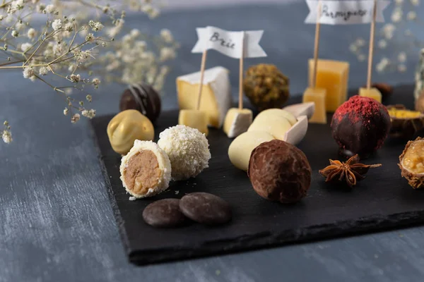 Handmade chocolate cheese candies, white, dark and milk chocolate and different sorts of cheese on the plate. Dessert foe gourmet