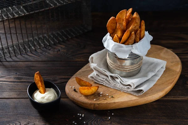 Fried Country-style Potato wedges, salt and sauce on wooden background. Copy space