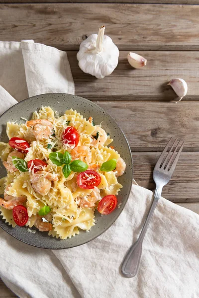 Farfalle and shrimps with garlic sauce, cherry tomatoes, and basil. Italian food, cuisine. Mediterranian menu. Top view, copy space