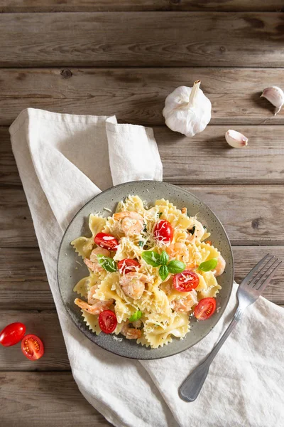 Farfalle and shrimps with garlic sauce, cherry tomatoes, and basil. Italian food, cuisine. Mediterranian menu. Top view, copy space for text