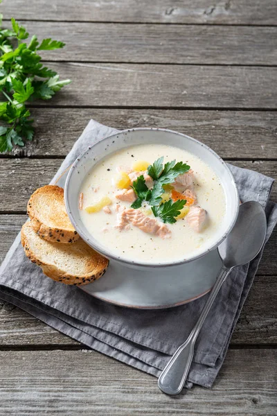Finnish salmon soup with cream on an old wooden background. Rustic style. Copy space