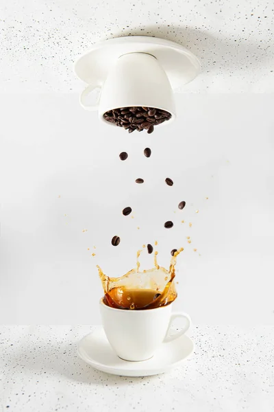 Coffee creative concept. Cup of coffee with splash and cup of coffee beans with levitation on white background. Coffee house