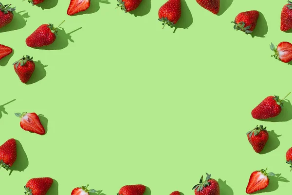 Strawberry seamless pattern frame with copy space for text. red ripe strawberries on green colored background, top view, flat lay, summer pattern. Trendy wallpaper background.