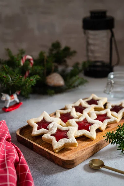 Traditional Christmas Linzer cookies with raspberry jam in star shape on dark background. Austrian biscuits filled. Christmas food, cookies. Holiday concept, vertical
