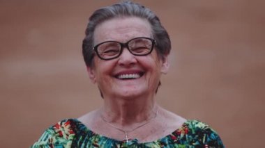 Kameraya bakarak gülümseyen yaşlı kadın