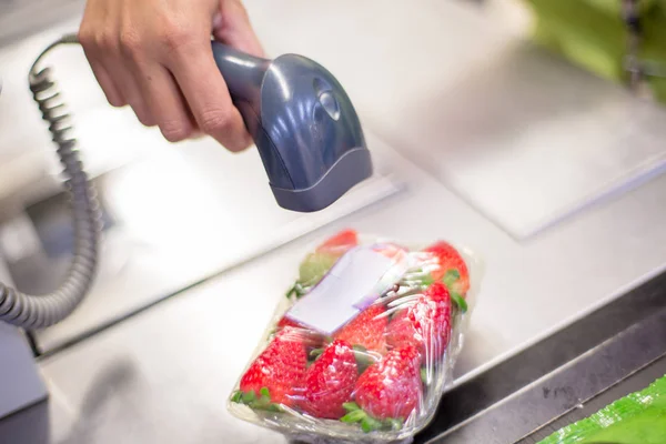 Bar code reader reading the code of a packet of strawberries on the checkout in a supermarket