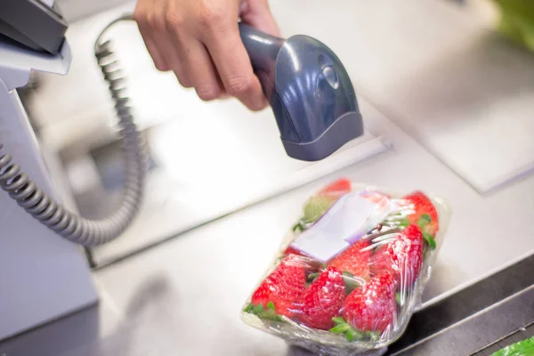 Bar code reader reading the code of a packet of strawberries on the checkout in a supermarket