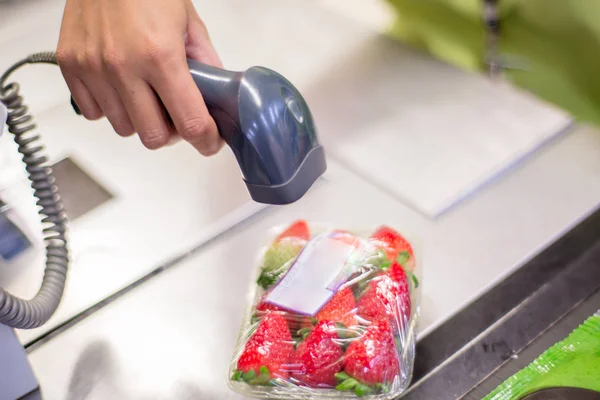 Bar code reader reading the code of a packet of strawberries on the checkout in a supermarket