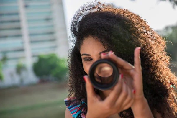 Black woman holding a camera len outside