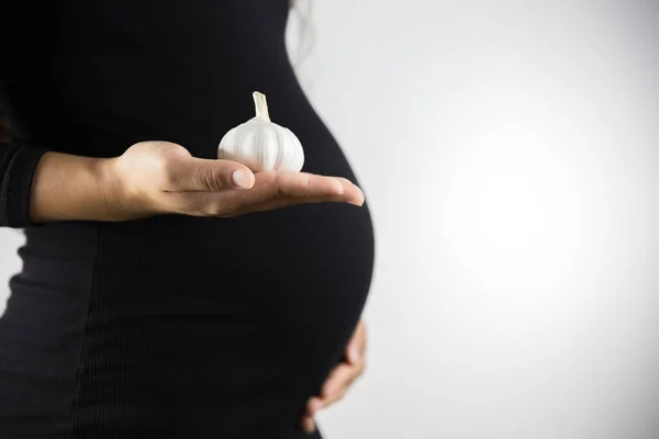 The consumption of garlic during pregnancy. Healthy food and people concept. Pregnant woman eat garlic.