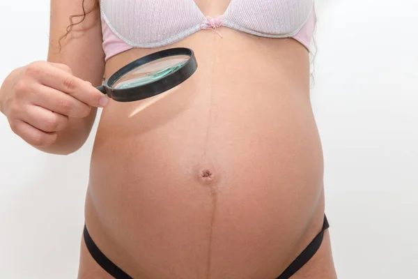 Kobieta Patrząc Brzuchu Ciąży Lupą — Zdjęcie stockowe