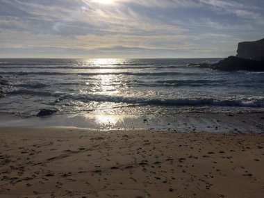 su üzerinde güneş parlama, deniz üzerinde gün batımı, kum ayak izleri, ıslak kum, sörf, deniz kayalar