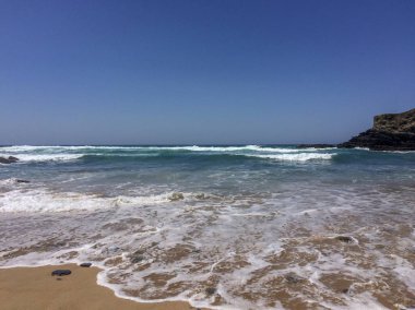 kumlu bir plajda dalgalar rulo, güzel güneşli gün, deniz köpüğü, kayalar