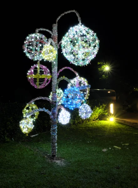 Shiny, glowing street decorations in the shape of a tree. Night scene