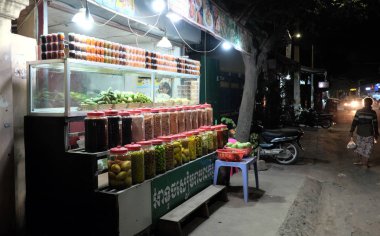 Siem Reap, Kamboçya, 13 Aralık 2018 büfebaharat ve konserve meyve satıyor. Baharat kavanozları ve konserve meyveleri olan bir raf. Sokak ticareti.